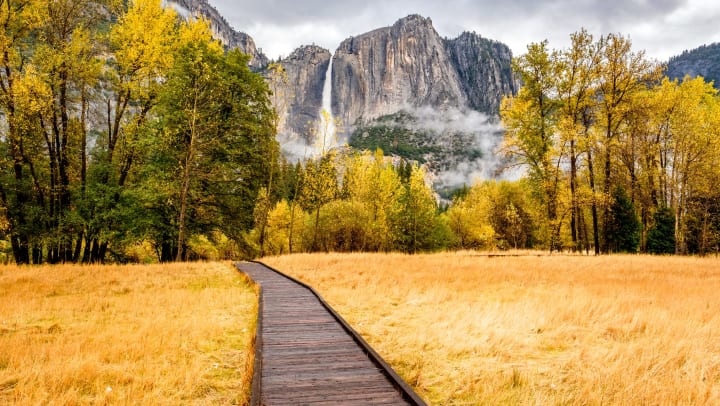 A picture of Yosemite Valley in Yosemite National Park with a boardwalk in the foreground and Yosemite Falls in the background