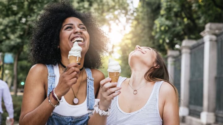Two friends outside laughing and eating ice cream