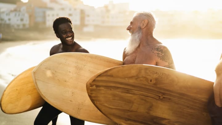 two people laughing while holding surf boards