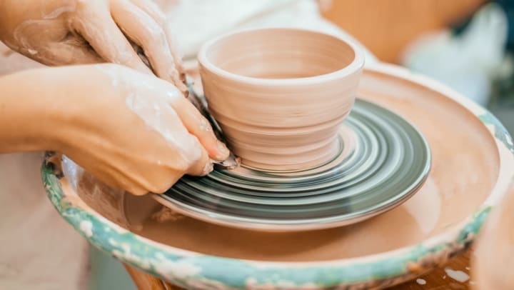 hands and a sculpting tool help form a clay bowl on a potter’s wheel | pottery classes in Santa Fe