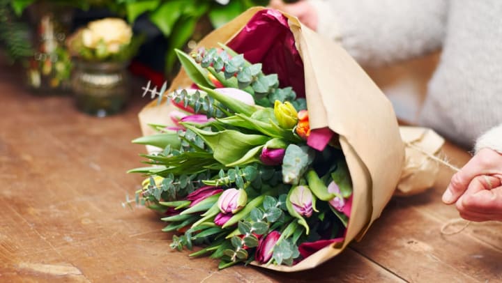 pink, orange, and yellow tulips wrapped in brown paper set on a table | Florists in Keller