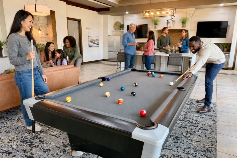 Group of residents in the clubhouse and playing pool at The Abbey at Preserve Way in Tomball, Texas
