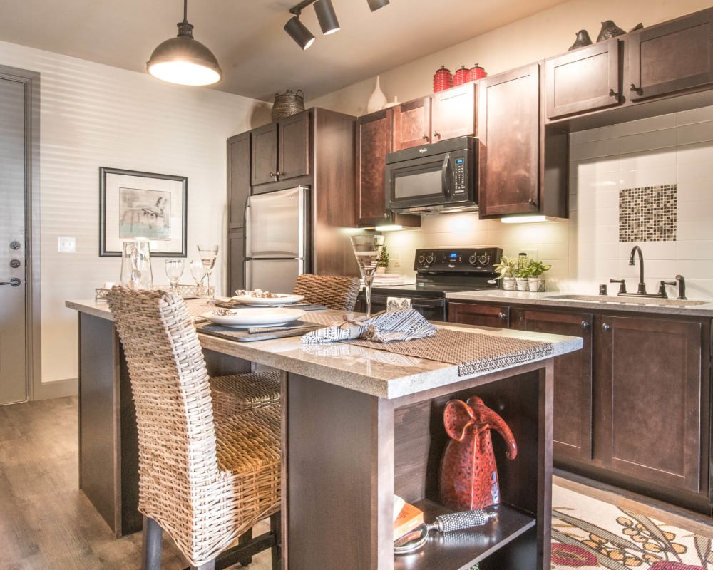 Open-concept gourmet kitchen with an island granite countertops in a model home at Union At Carrollton Square in Carrollton, Texas