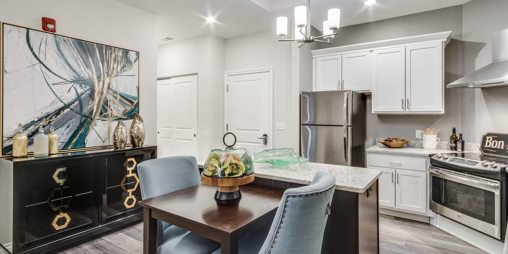 Upscale senior dining room and kitchen with stainless steel appliances and hardwood floors at Blossom Collection in Rochester, Michigan