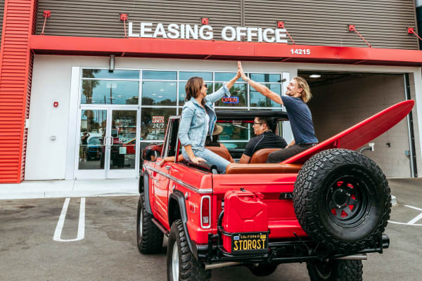 Friends high-fiving in jeep outside StorQuest Self Storage