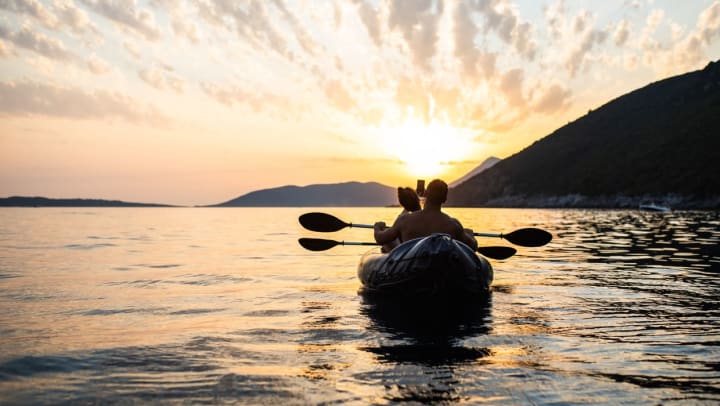Two people sharing kayak on a lake at sunset