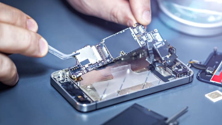 A technician repairing a damaged cell phone