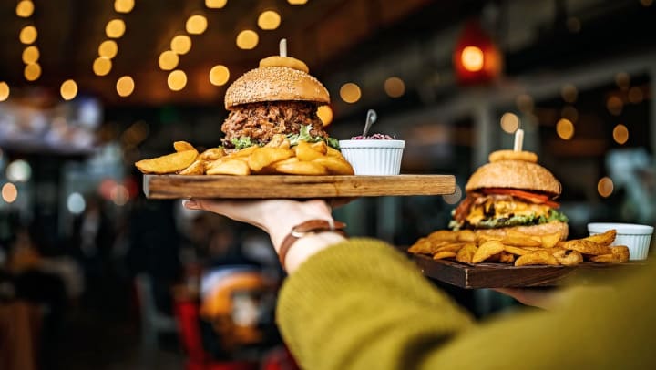 hand holds up a tray of American-style food including a burger and fries at a restaurant | American restaurants in Twin Falls