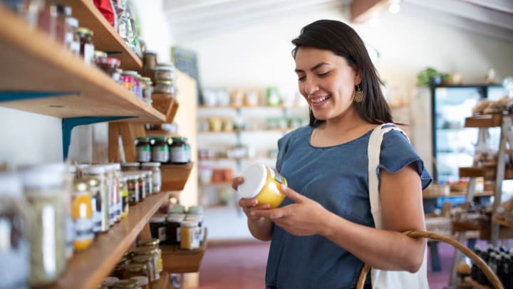 Woman looking at a jar of preserves at a food store | specialty food stores in Las Cruces