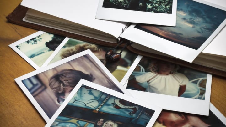 polaroid pictures scattered across a table and coming out of a photo album | tips to make your home feel nostalgic