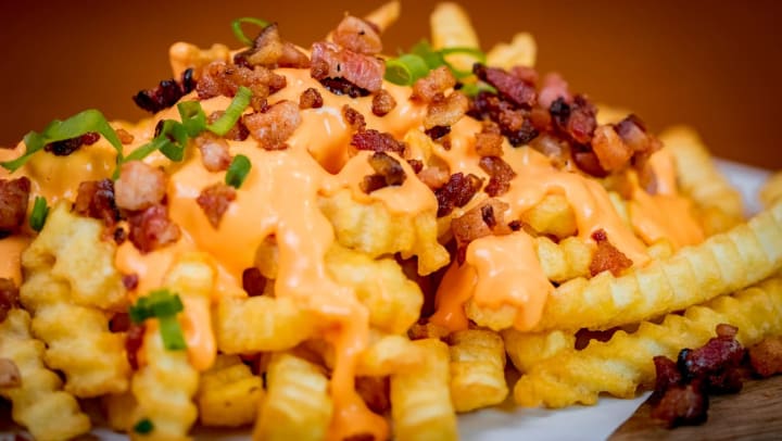 close up of loaded fries with cheese, bacon, and green onions