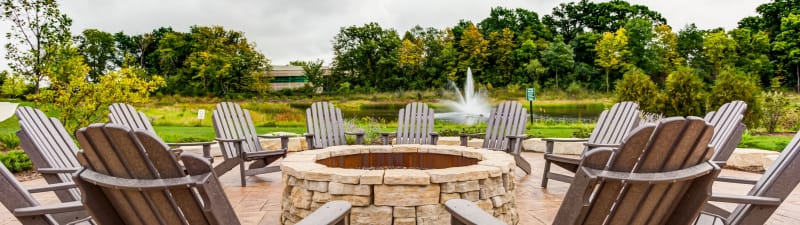 Beautiful waterfront fire pit surrounded by comfortable lawn chairs at The Oaks Of Vernon Hills's lobby in Vernon Hills, Illinois