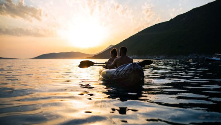 Two people sitting in a kayak paddling on open water