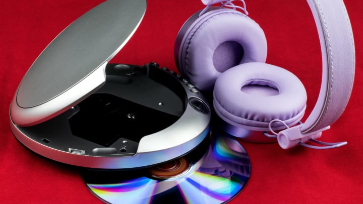 A pair of headphones, a portable disk player, and a CD.