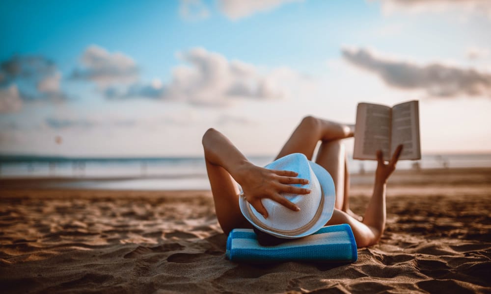 A resident reading a book on a beach near The Ascend at Pensacola Bay in Pensacola, Florida