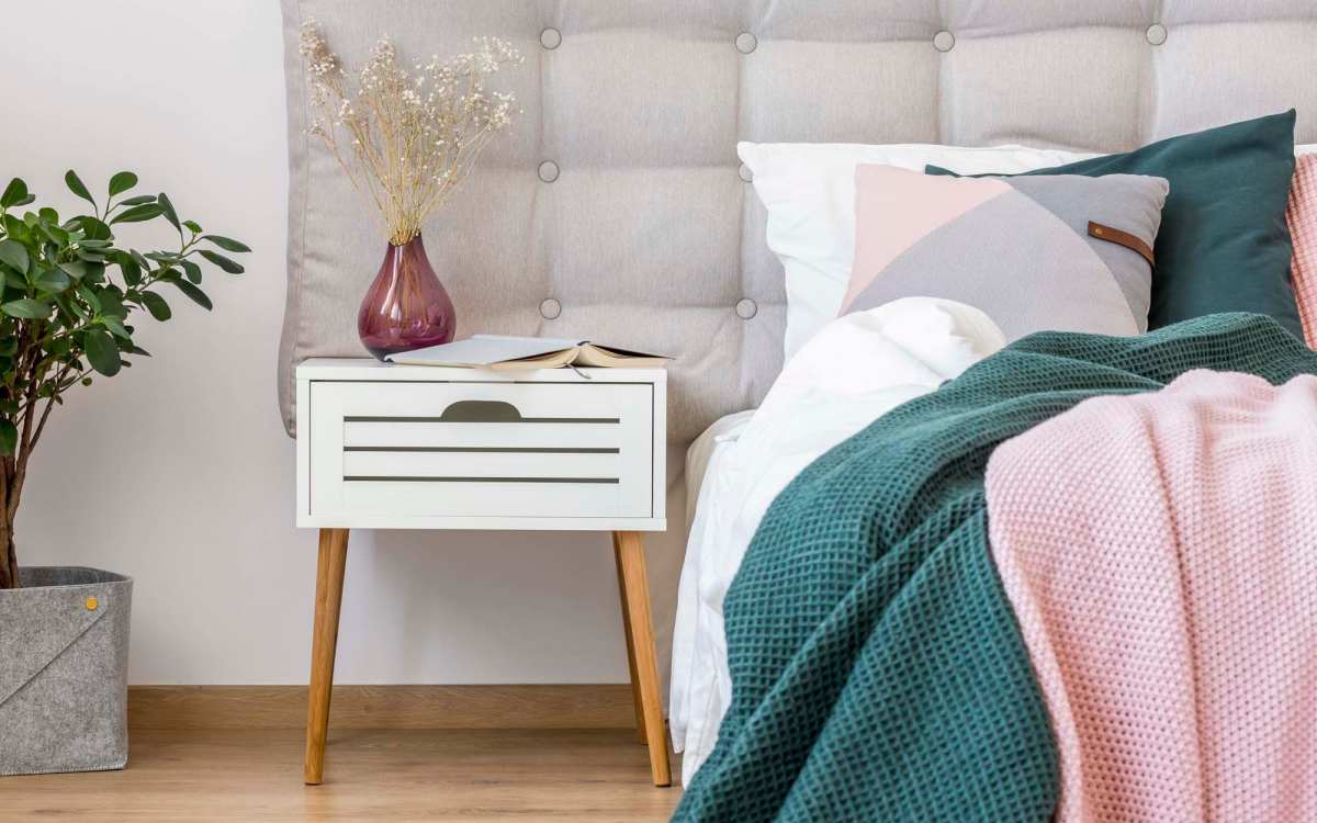 Spacious bedroom with large bed, side table and wood-style flooring at The Rose on Colfax in Denver, Colorado