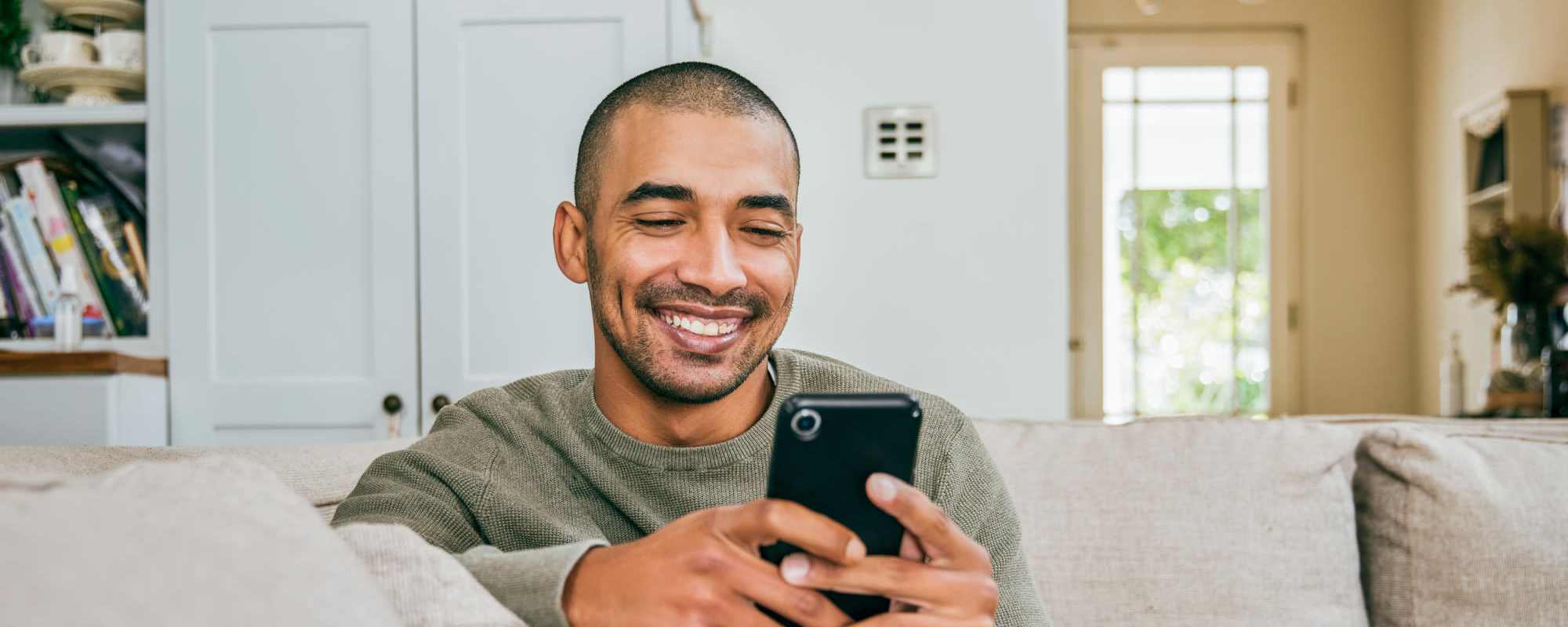 Residents | A resident smiling as he uses his phone at The Lido Apartments in Los Angeles, California