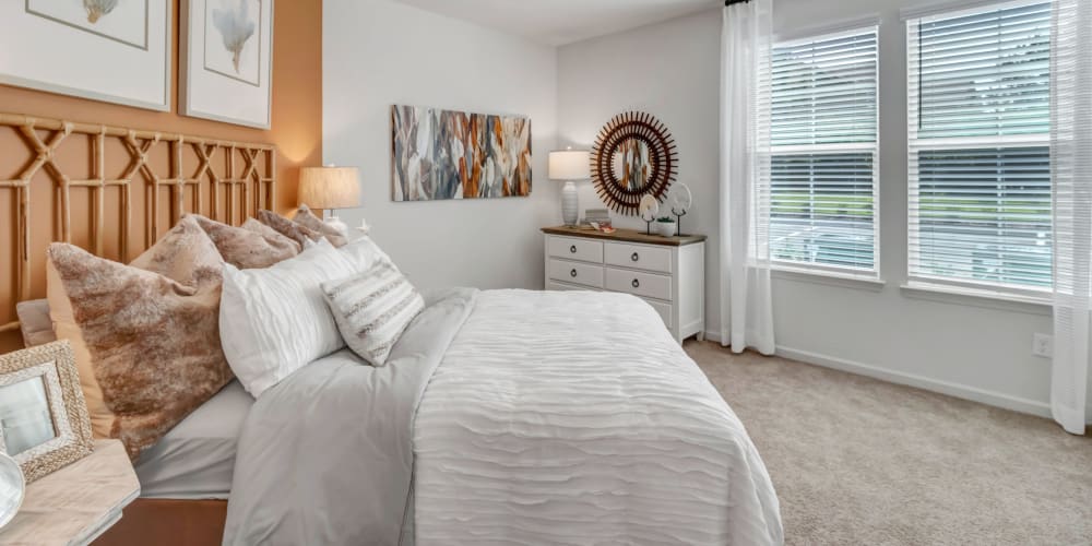 Well-furnished primary bedroom with large windows in a model apartment at Tapestry Westland Village in Jacksonville, Florida