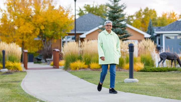 Resident walking through community filled with colorful autumn leaves