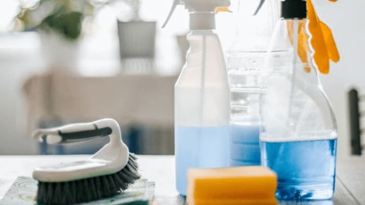 A table displaying various cleaning supplies alongside a bottle of cleaning solution.