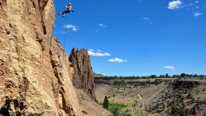 Rock climber scaling Smith Rock on a sunny day