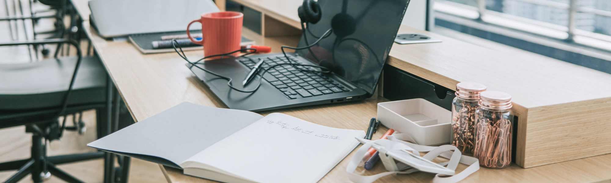 Modern workspace with laptop, coffee mug, notebook, and organized stationery on wooden desk at Union Place Apartments in Lafayette, Indiana