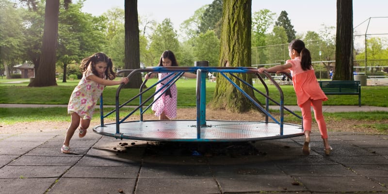 Kids playing on a merry-go-round near Barclay Square Apartments in Baltimore, Maryland