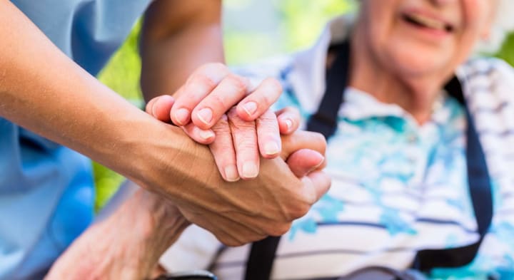 Caregiver and senior holding hands