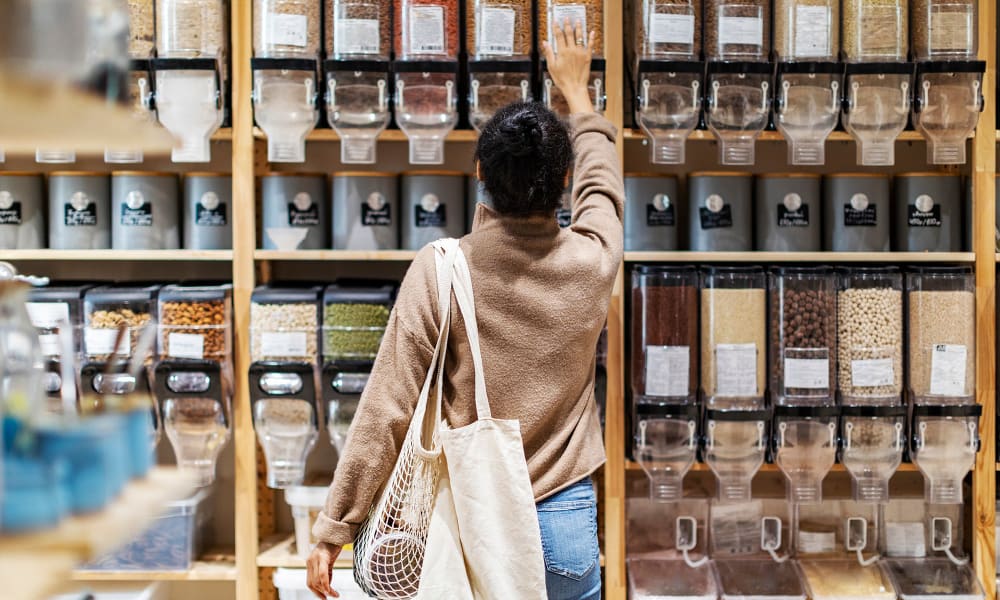 A woman reaching for an item on a shelf in a grocery store near Verandahs at Cliffside Apartments in Arlington, Texas