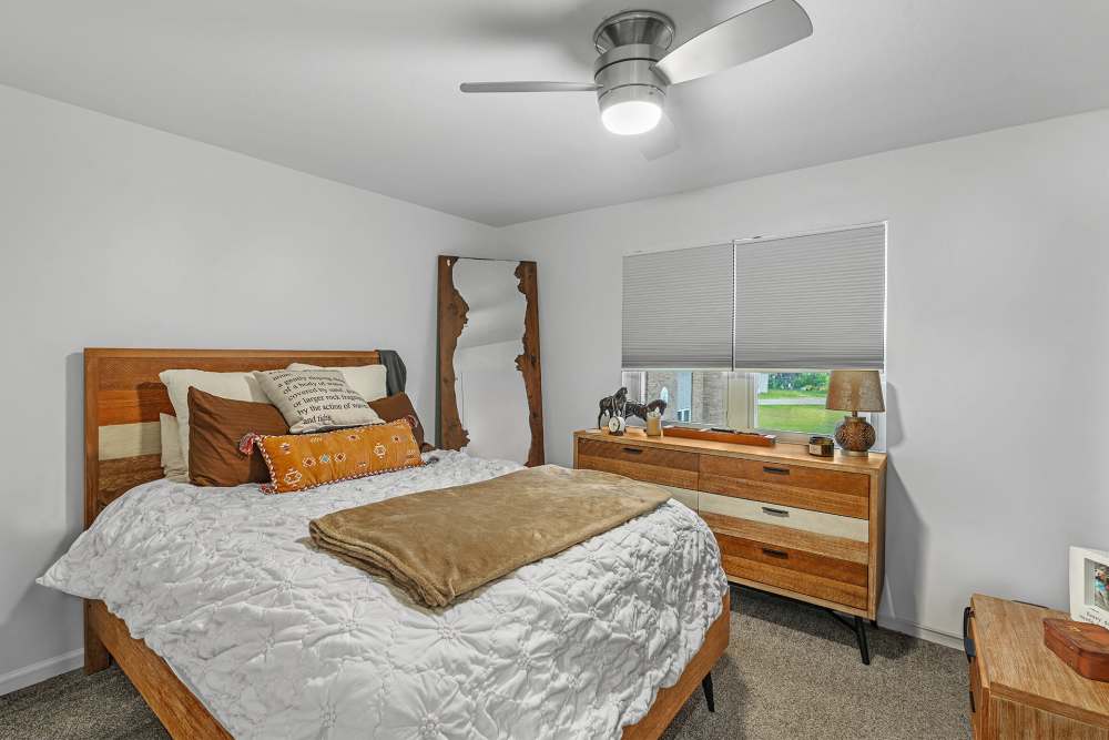 Modern bedroom with king size bed, ceiling fan, carpet flooring and large window at Tyndall Pointe in Panama City, Florida