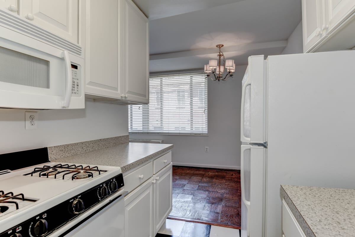 White cabinets and appliances in the kitchen next to the dark wood floors in the living area at Hill House in Washington, District of Columbia
