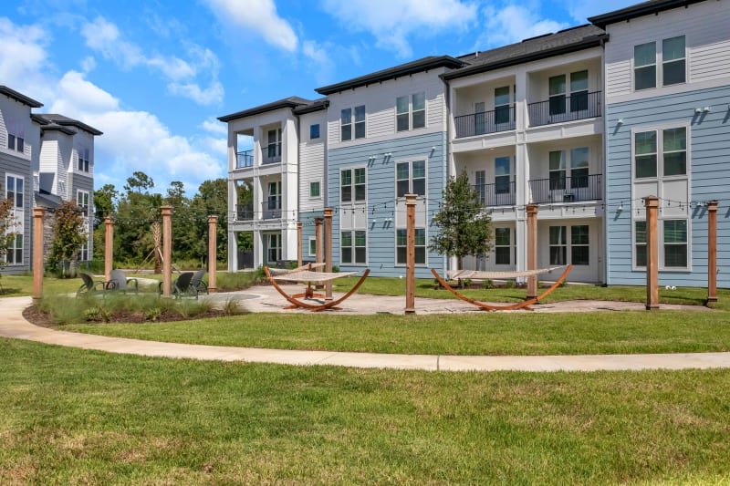 Well-kept green grass and patio with hammocks outside resident buildings at Tapestry Westland Village in Jacksonville, Florida