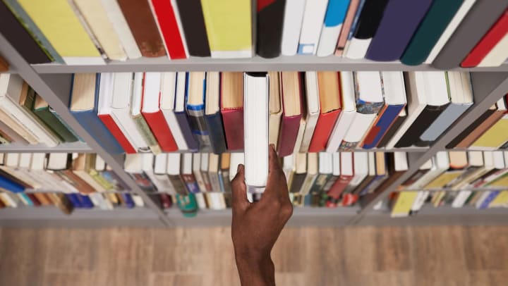 A close-up of someone’s hand pulling a book off a shelf in a Fort Worth bookstore.