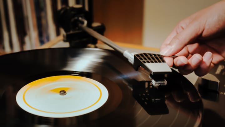 A hand placing the needle on a record player | record stores in Nashville