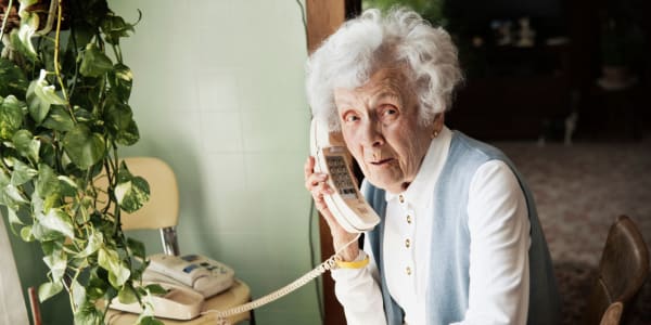 Resident sitting at her dining table talking on home phone at Wellington Place at Fort Atkinson in Fort Atkinson, Wisconsin