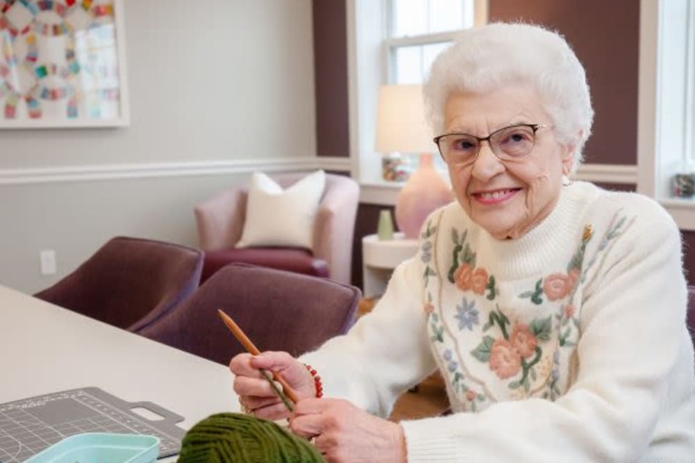 A smiling resident knitting at Crescent Fields at Huntingdon Valley in Huntingdon Valley, Pennsylvania