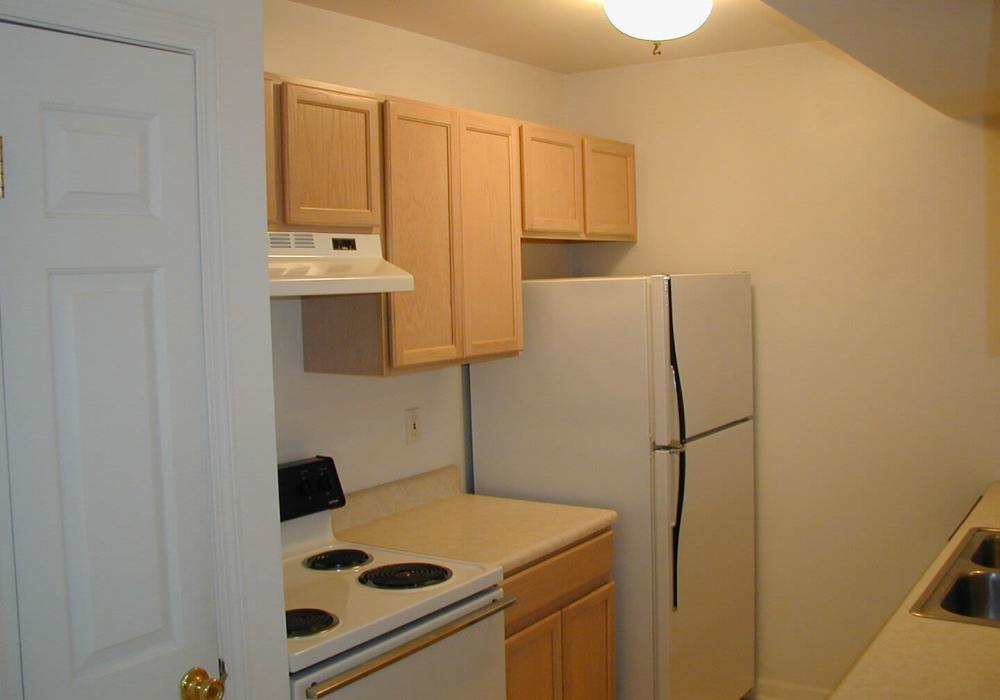 Compact kitchen with cabinets and appliances at North Road Townhomes in Scottsville, New York