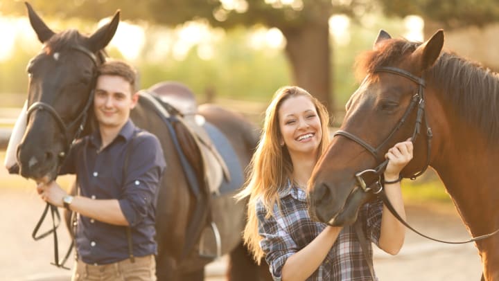 A smiling man and woman with horses 
