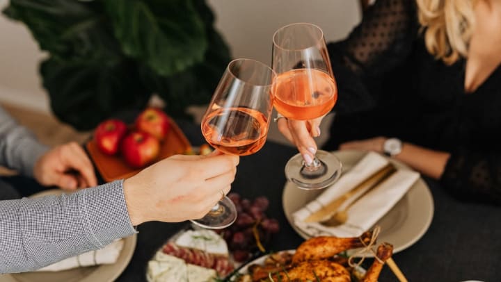 two people doing a cheers with rosé wine over a chicken dinner | spring recipes 