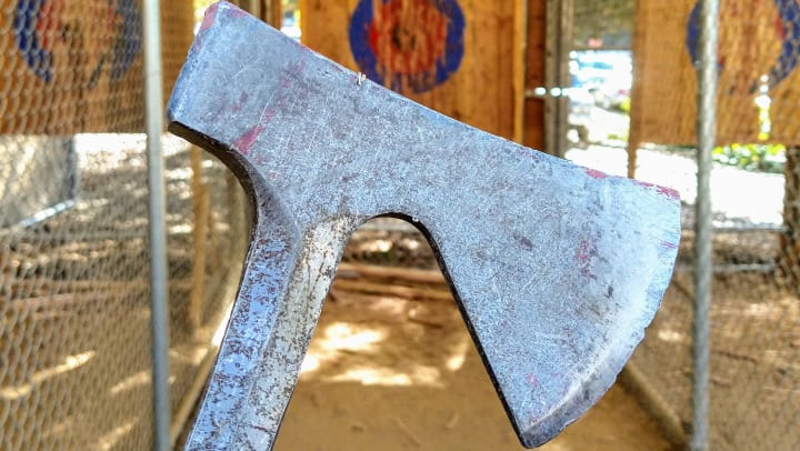 Close-up of an ax with a target in the background. 