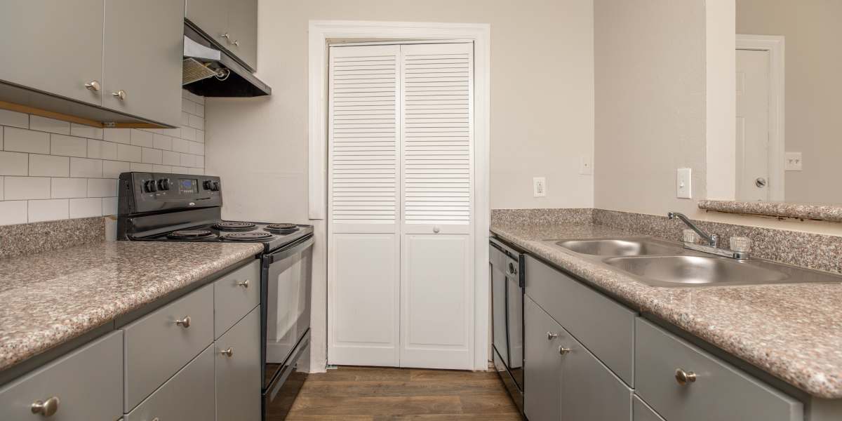 Apartment kitchen with granite countertop and wood-style flooring at Fredericksburg Place Apartments in San Antonio, Texas