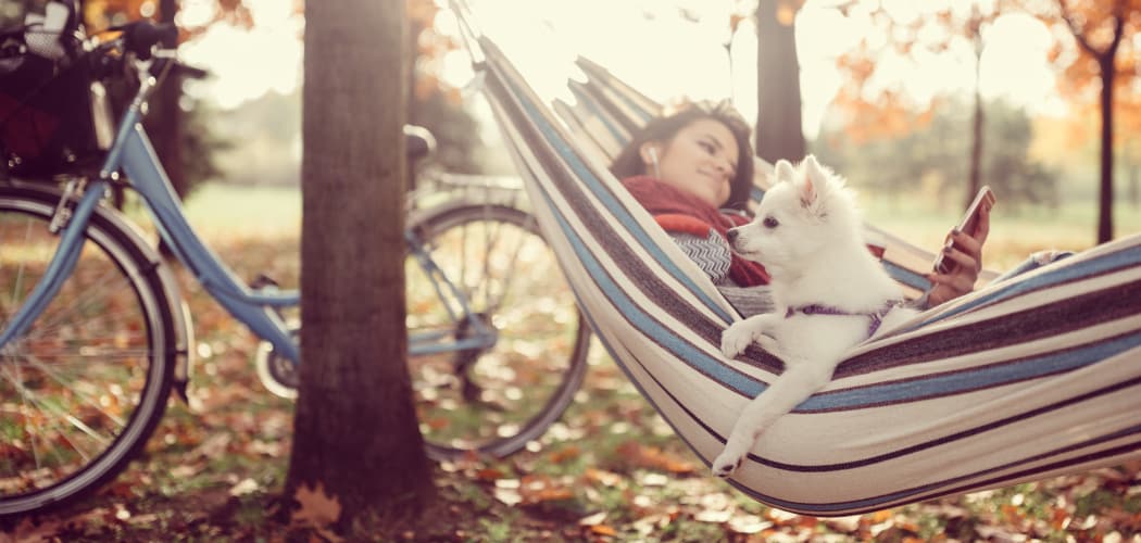 Resident and her dog relaxing in a hammock among the trees at Residences at Sonoma Woods in Newport News, VA