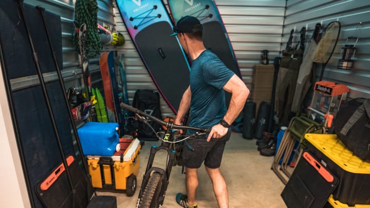A man pulling out a mountain bike from other summer gear storage area