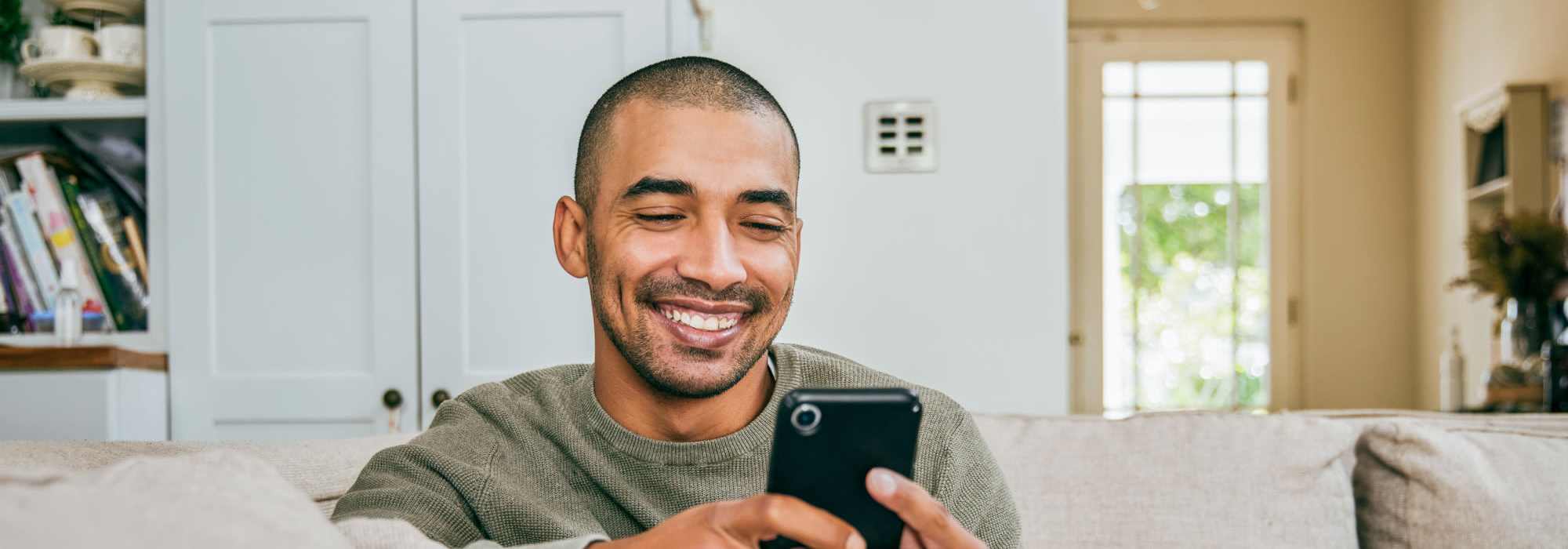 Residents | A man smiling at his phone at Brentwood Apartments in Portland, Oregon