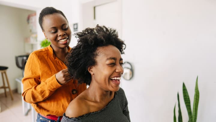 A young woman hairdresser giving a haircut to her female customer in one of the hair salons around Katy.