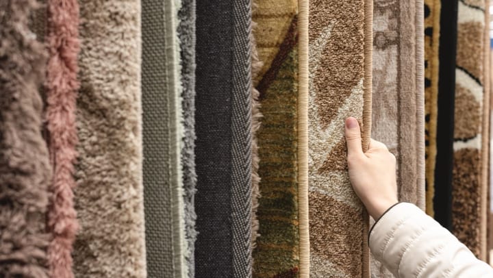 Close up of a person looking at rugs hanging in a store | Rug Stores Around Fort Worth