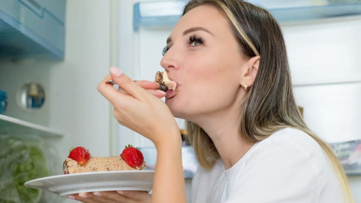 Resident taking a bite from a slice of ice cream cake in her apartment at Olympus Steelyard in Chandler, Arizona