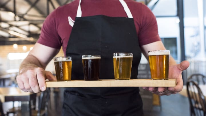Server carrying a a flight of beers to a table at a restaurant near Olympus at Auburn Lakes