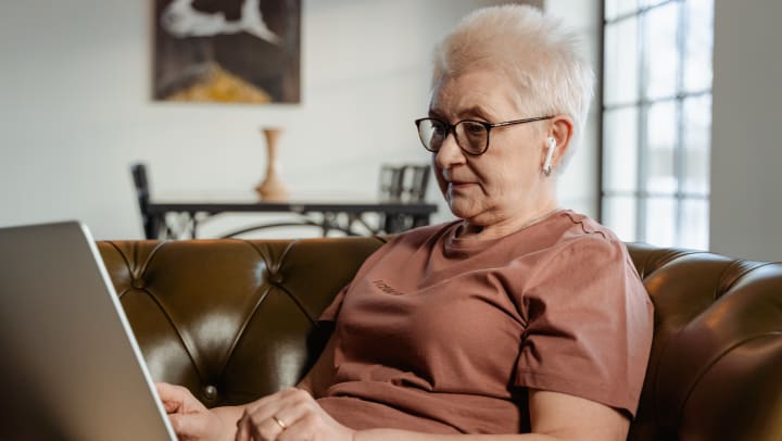Elderly woman using a laptop on a couch