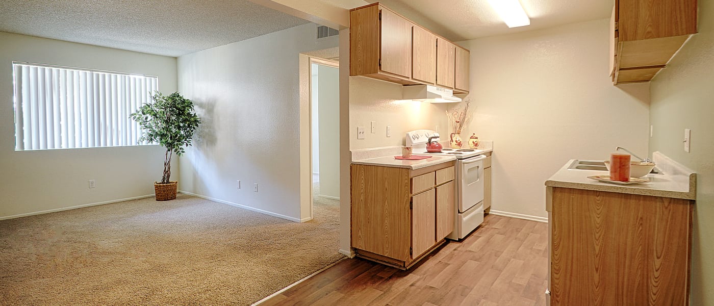 Upgraded kitchen with partial view of plush carpeting in living area at Creekside Village Apartment Homes in San Bernardino, CA